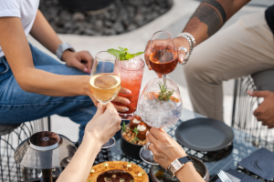 Drie vrouwen en een man proosten met witte wijn, rosé en twee cocktails.