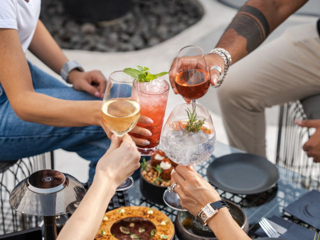 Drie vrouwen en een man proosten met witte wijn, rosé en twee cocktails.