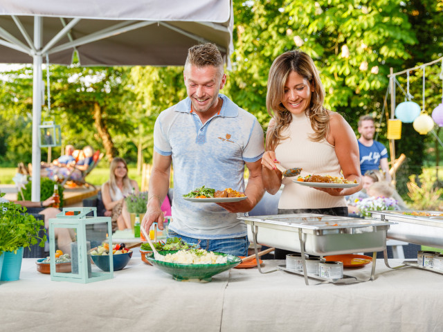 Twee personen scheppen hun bord vol met een heerlijk buffet